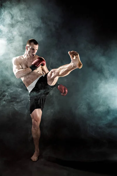 Muscular kickbox ou muay thai lutador perfurando na fumaça . — Fotografia de Stock