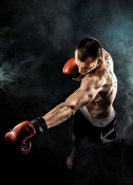 Muscular kickbox o muay thai luchador puñetazos en el humo . — Foto de Stock