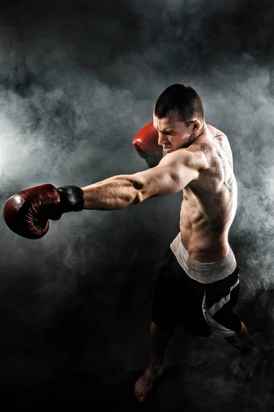 Muscular kickbox o muay thai luchador puñetazos en el humo . — Foto de Stock