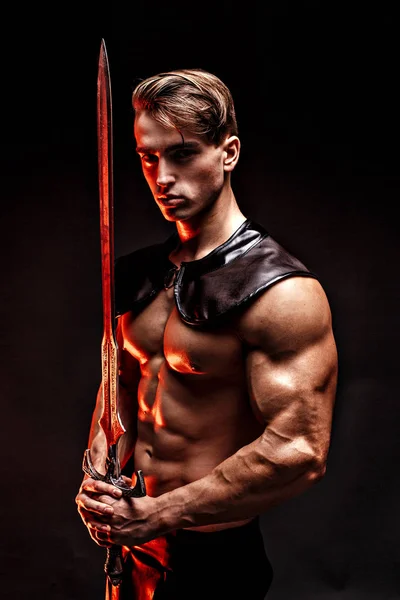 Portrait of sexy muscular man holding sword and looking at camera . — Stock Photo, Image
