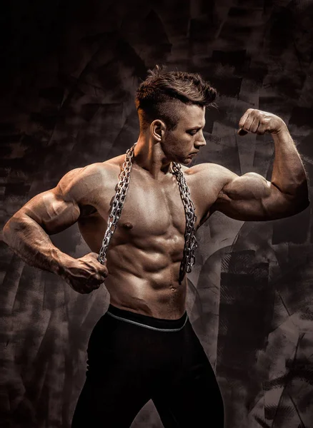 Le corps masculin parfait - Super bodybuilder posant. Tenir une chaîne avec tatouage — Photo