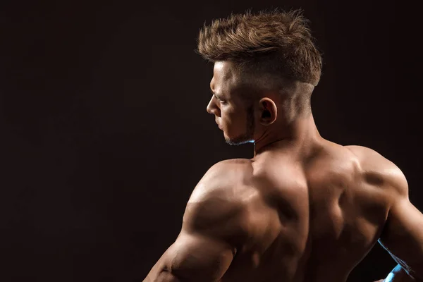 Sterke atletische man fitness model poseren rugspieren, triceps, latissimus op zwarte achtergrond — Stockfoto