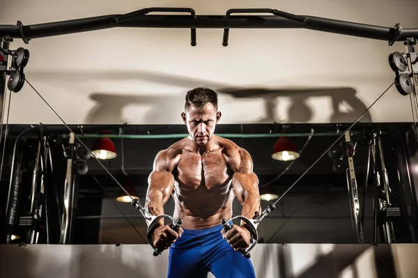Jeune bodybuilder travaille sur sa poitrine avec câble croisé dans la salle de gym — Photo