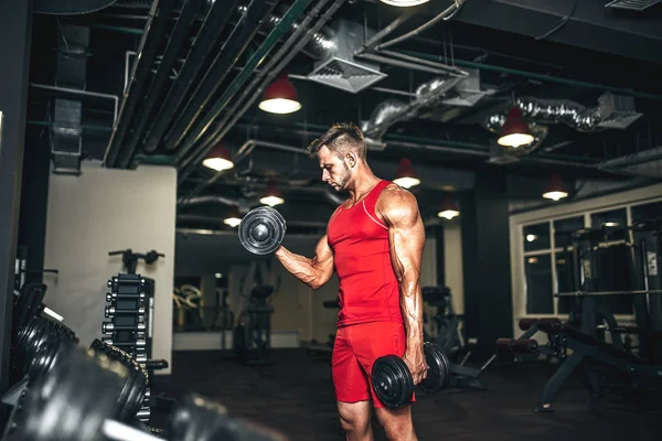 Culturista determinado levantando pesadas mancuernas negras en el gimnasio . —  Fotos de Stock