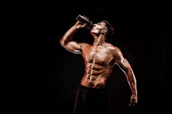 Muskulöser Mann mit Proteingetränk im Shaker vor dunklem Hintergrund — Stockfoto