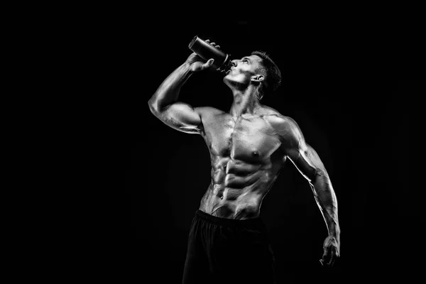 Hombre musculoso con bebida proteica en coctelera sobre fondo oscuro —  Fotos de Stock