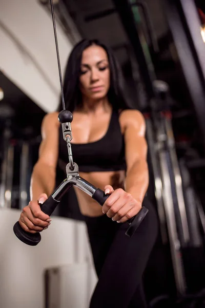Vrouw buigen spieren op kabel machine in sportschool — Stockfoto