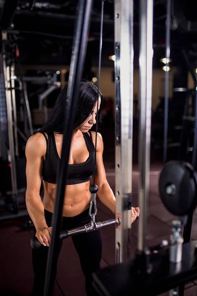 Kvinna som flexar muskler på kabel maskin i gymmet — Stockfoto