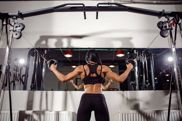 Žena, protahuje svaly na kabel stroj v tělocvičně — Stock fotografie