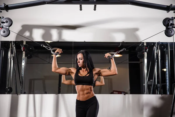 Donna che flette i muscoli sulla macchina via cavo in palestra — Foto Stock