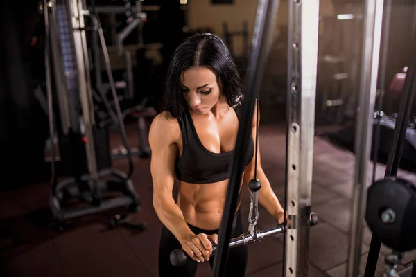 Mulher flexionando músculos na máquina de cabo no ginásio — Fotografia de Stock