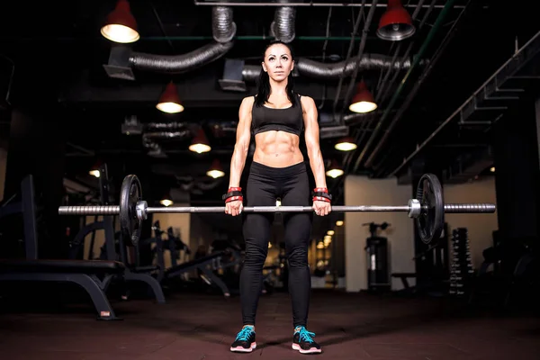 Musclé jeune femme de remise en forme faisant l'exercice lourd deadlift dans la salle de gym — Photo