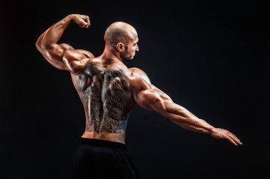 Siyah arka plan karşı sırtına dövme tanınmaz kaslı adam. İzole.