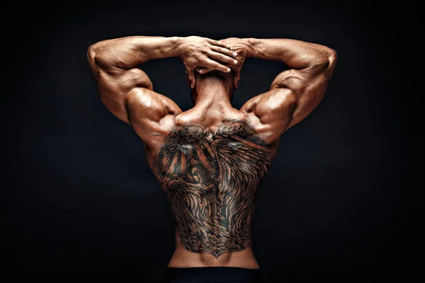 Homem musculoso irreconhecível com tatuagem nas costas contra fundo preto. Isolados . — Fotografia de Stock