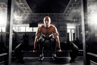 Spor salonunda Deadlift egzersiz yaparak genç gömleksiz adam.
