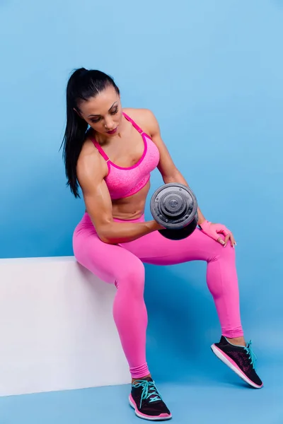 Donna muscolosa in leggings rosa, top e guanti allenamento con manubri. Isolato — Foto Stock