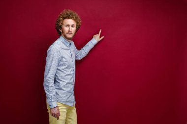 Boşluk işaret parmağı ile gösterilen tişörtlü kıvırcık saçlı adam