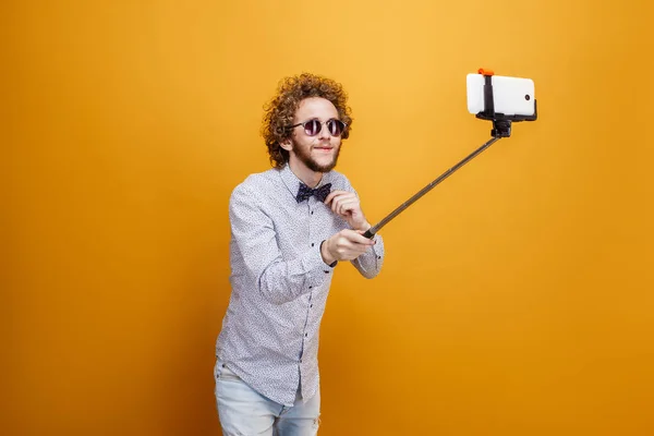 Curly-haired mens in zonnebrillen en ' bow-tie nemen selfie met behulp van m — Stockfoto