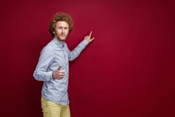 Hombre de pelo rizado con camisa mostrando espacio en blanco con el dedo índice — Foto de Stock