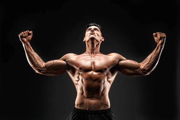 Culturista in posa. Bellissimo ragazzo sportivo potere maschile. Uomo muscoloso fitness. Guardando e alzando le mani . — Foto Stock