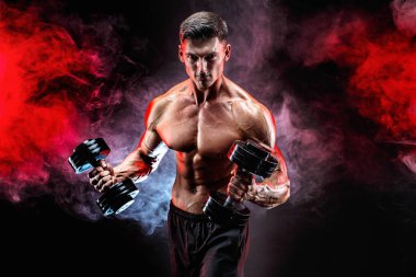 Konsantre olmuş kaslı adam dambılla egzersiz yapıyor.