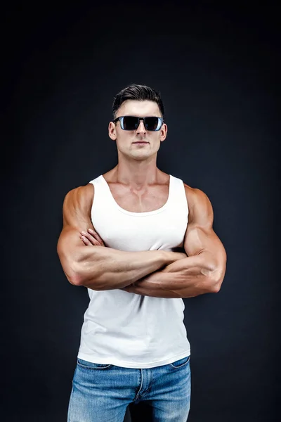 Bonito homem musculoso em óculos escuros e uma camisa branca . — Fotografia de Stock