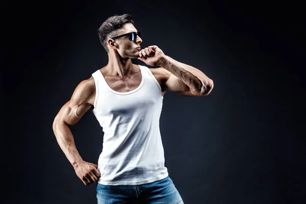 Bello uomo muscoloso in occhiali scuri e una camicia bianca . — Foto Stock