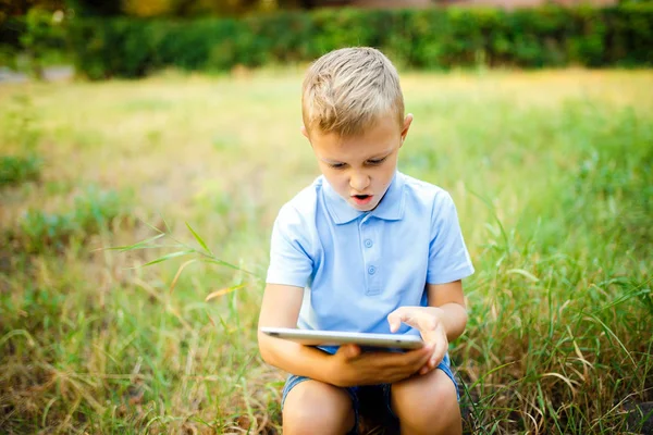 タブレット pc でゲームをプレイ フォレストで座っている若い子供. — ストック写真