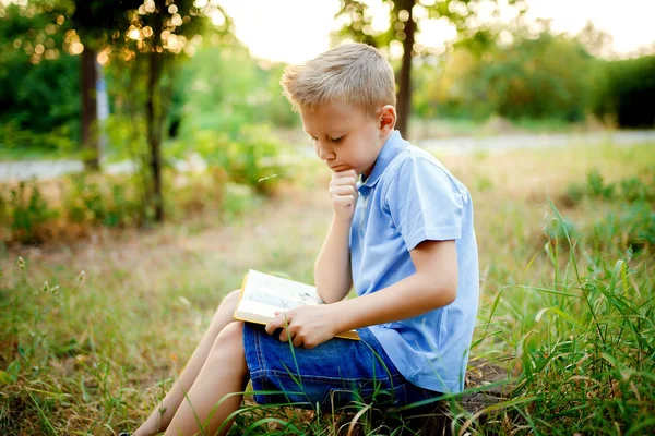 Gyerek ül az erdő, a könyv a térdet . — Stock Fotó