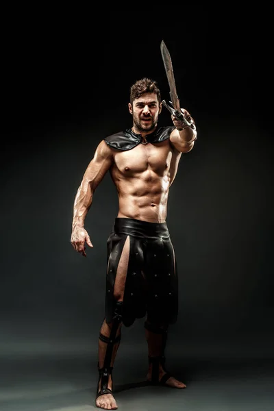 Severe barbarian in leather costume with sword — Stock Photo, Image