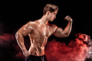 Güçlü vücut geliştirmeci adam mükemmel abs, omuzlar, pazı, triceps, göğüs kadar duman elinde poz ile.