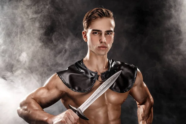 Retrato de guapo gladiador muscular con espada. Aislado. Grabado en estudio. Fondo negro — Foto de Stock