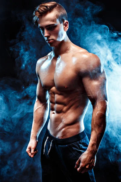 Ισχυρή bodybuilder με έξι pack, τέλειους κοιλιακούς, τους ώμους, δικέφαλου, τρικέφαλος μύς και στο στήθος, προσωπικό γυμναστή κάμψη τους μυς του στον καπνό — Φωτογραφία Αρχείου
