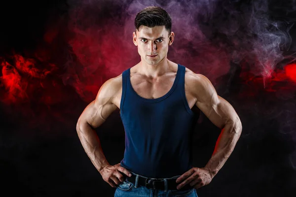 Testépítő pózol. Szép sportos srác férfi erő. Fitness izmos férfi ing, sötét füstös háttér — Stock Fotó