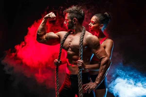 Bodybuilders poseren met touw en rook rond. — Stockfoto