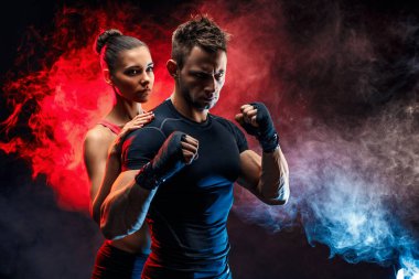 Güçlü boksör yumruklarını üzerinde handwraps ile duruş. Onun arkasında duran kız arkadaşıyla.