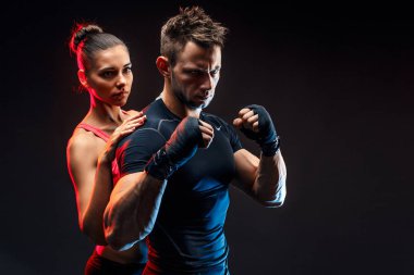 Güçlü boksör yumruklarını üzerinde handwraps ile duruş. Onun arkasında duran kız arkadaşıyla.