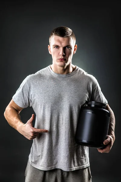 Bonito jovem atlético homem segurando um frasco de nutrição esportiva — Fotografia de Stock