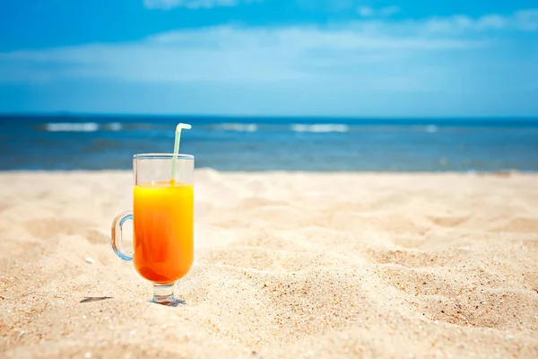 Jugo en un vaso sobre fondo borroso del paisaje marino — Foto de Stock