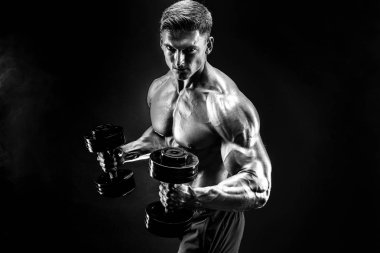 Yakışıklı vücut dumbbell egzersiz yapıyor. Stüdyo vurdu. Siyah ve beyaz fotoğraf. Duman