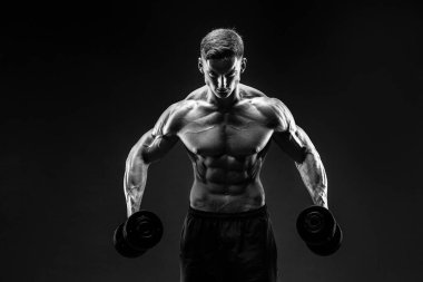 Yakışıklı vücut dumbbell egzersiz yapıyor. Stüdyo vurdu. Siyah ve beyaz fotoğraf.