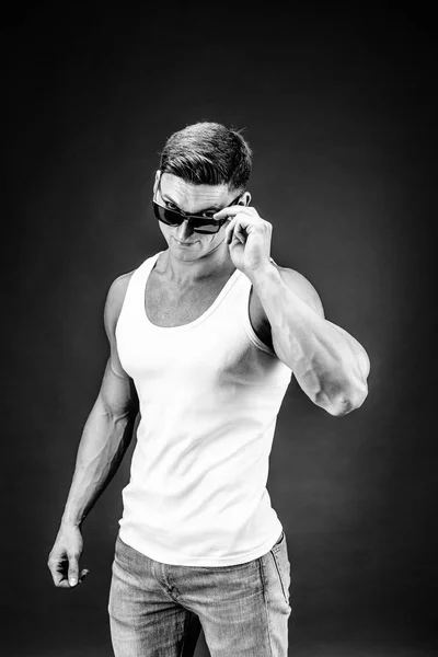 Bonito homem musculoso em óculos escuros e uma camisa branca . — Fotografia de Stock