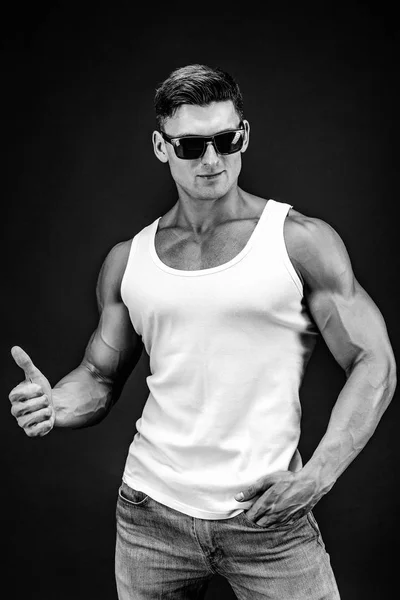 Bonito homem musculoso em óculos escuros e uma camisa branca . — Fotografia de Stock