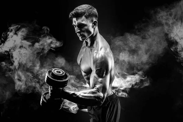 Gutaussehender Bodybuilder beim Training mit der Hantel. Studioaufnahmen. Schwarz-Weiß-Foto. Rauch — Stockfoto