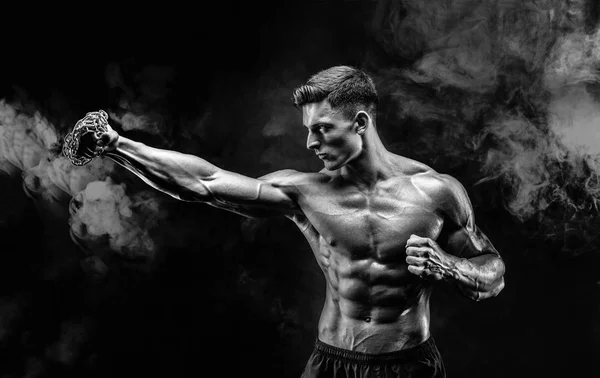 Серйозний м'язовий боєць робить удар з ланцюгами, заплетеними над його кулаком . — стокове фото