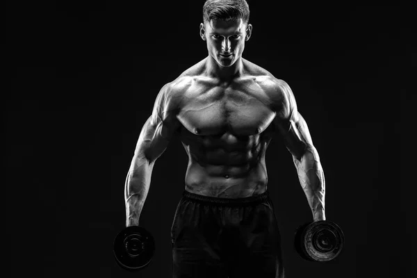 Handsome bodybuilder doing exercise with dumbbell. Studio shot. Black and white photo. — Stock Photo, Image