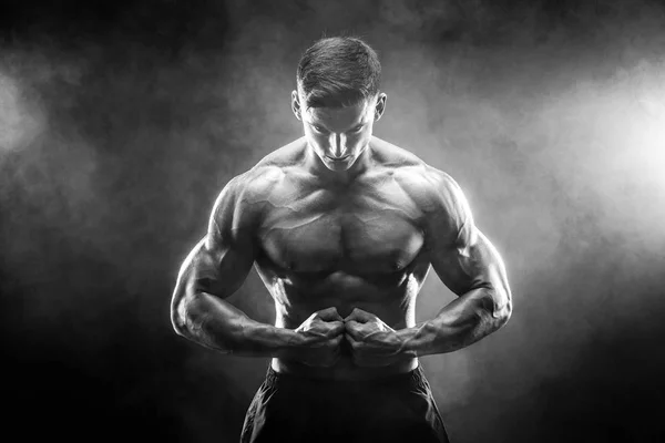 Ισχυρή bodybuilder άνθρωπος με τέλειο σώμα-abs, δικέφαλου, τρικέφαλος μύς, ώμους, στήθος θέτοντας σε φόντο καπνού στούντιο — Φωτογραφία Αρχείου