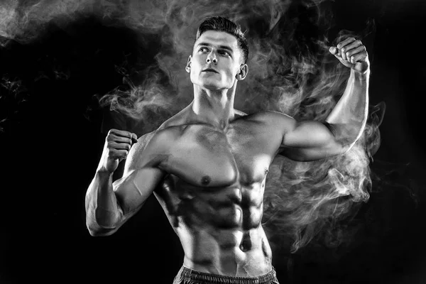 Hombre fuerte culturista con cuerpo perfecto- abdominales, hombros, bíceps, tríceps, pecho posando en fondo de humo estudio — Foto de Stock