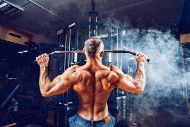 Arka üstünde makine için ağır egzersiz yaparak güçlü vücut geliştirmeci