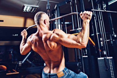 Arka üstünde makine için ağır egzersiz yaparak güçlü vücut geliştirmeci